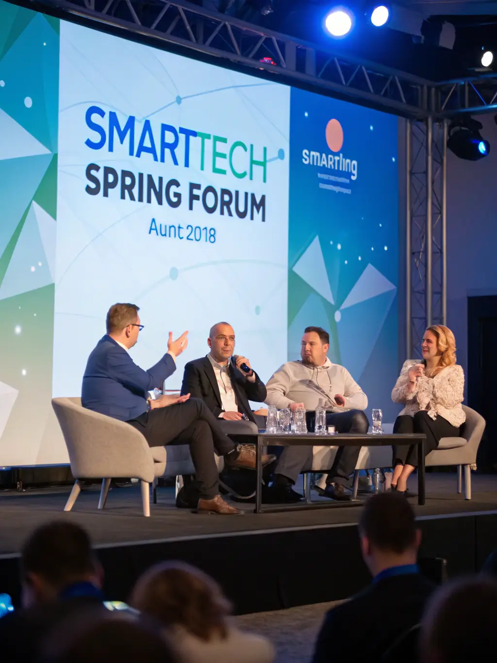 A photograph of a panel discussion in progress, featuring three speakers engaged in a lively debate on sustainable business practices, with the audience visible in the background. This image will be used to promote the panel discussion.